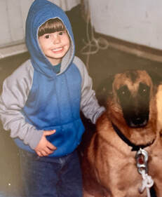 Picture of Dr. Kerr as a young boy (with fish-eating grin) with Belgian Malinois dog