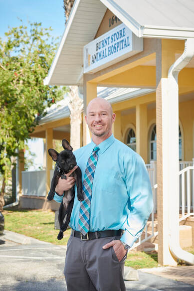 Picture of Dr. Justin Kerr, Dewey (black Frenchie) in front of Burnt Store Animal Hospital building
